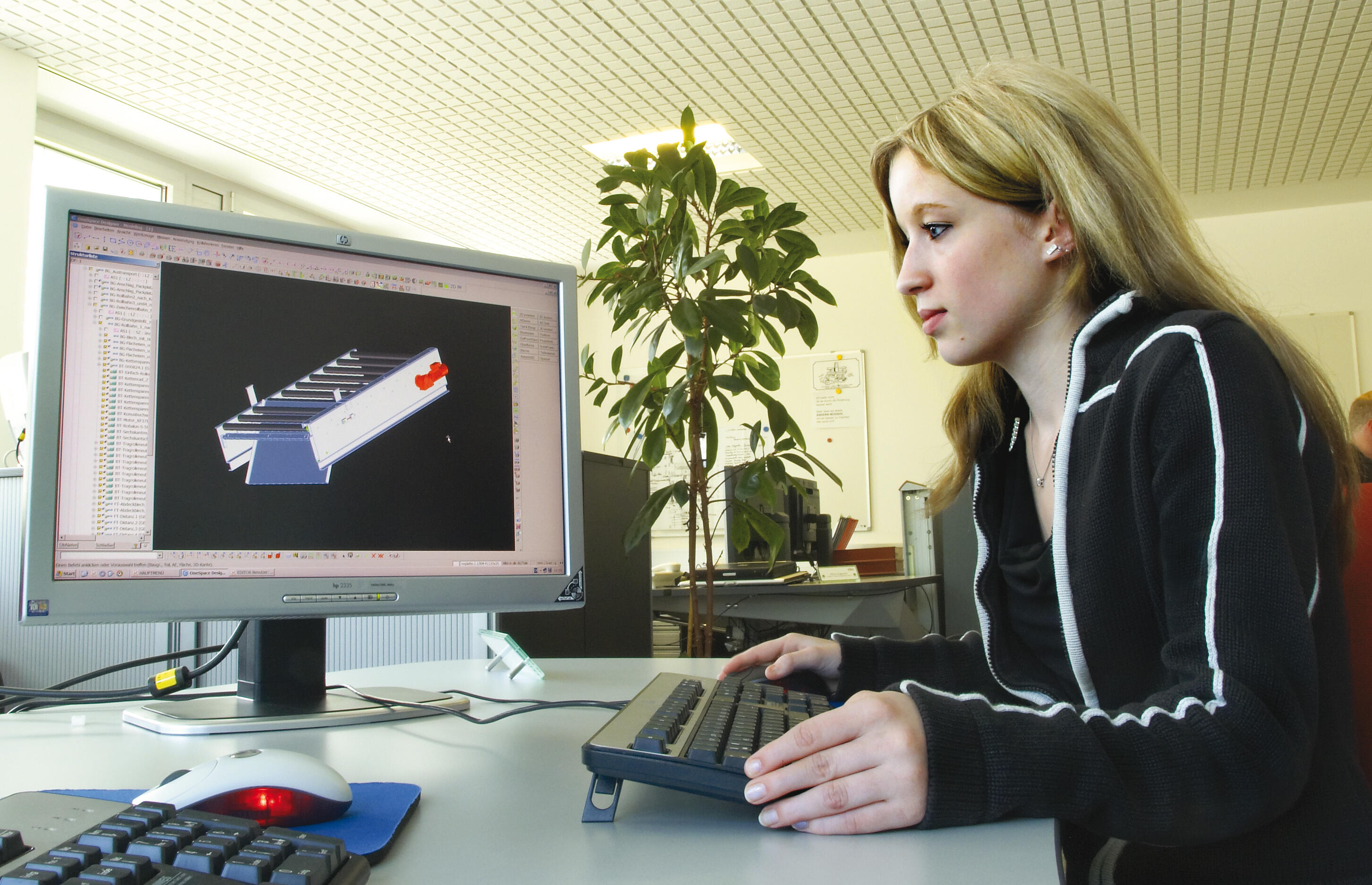 Eine junge Frau sitzt an ihrem Schreibtisch und konstruiert mit einem CAD-Programm.